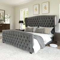 a bedroom with a grey upholstered bed